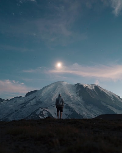 站在草地上俯瞰高山的人